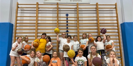Powiększ grafikę: Uczniowie z klasy 4A/B stoją w grupie trzymając piłki od koszykówki