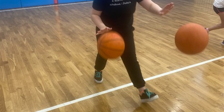 Powiększ grafikę: Julia kozłuje jednocześnie dwie piłki od koszykówki.