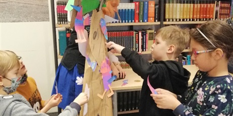 Powiększ grafikę: Dzieci z klasy Ia kleją kolorowe rajskie ptaki, magiczne zwierzęta i stwory.  Wszyscy samodzielnie przyklejają swoje dzieła na magicznym drzewie.